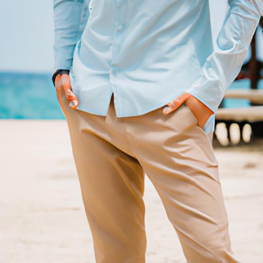 Một người đàn ông mặc áo sơ mi linen xanh nhạt và quần beige đứng bên bãi biển