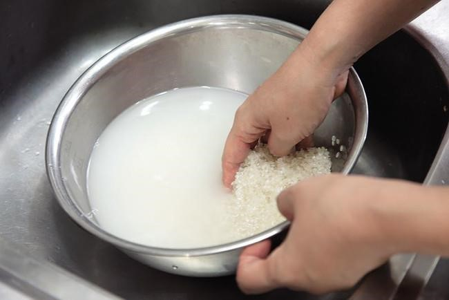 Bước 1: Sơ chế gạo bao gồm việc lựa chọn, rửa sạch và ngâm gạo để loại bỏ tạp chất và tăng độ mềm của hạt gạo trước khi đem nấu.